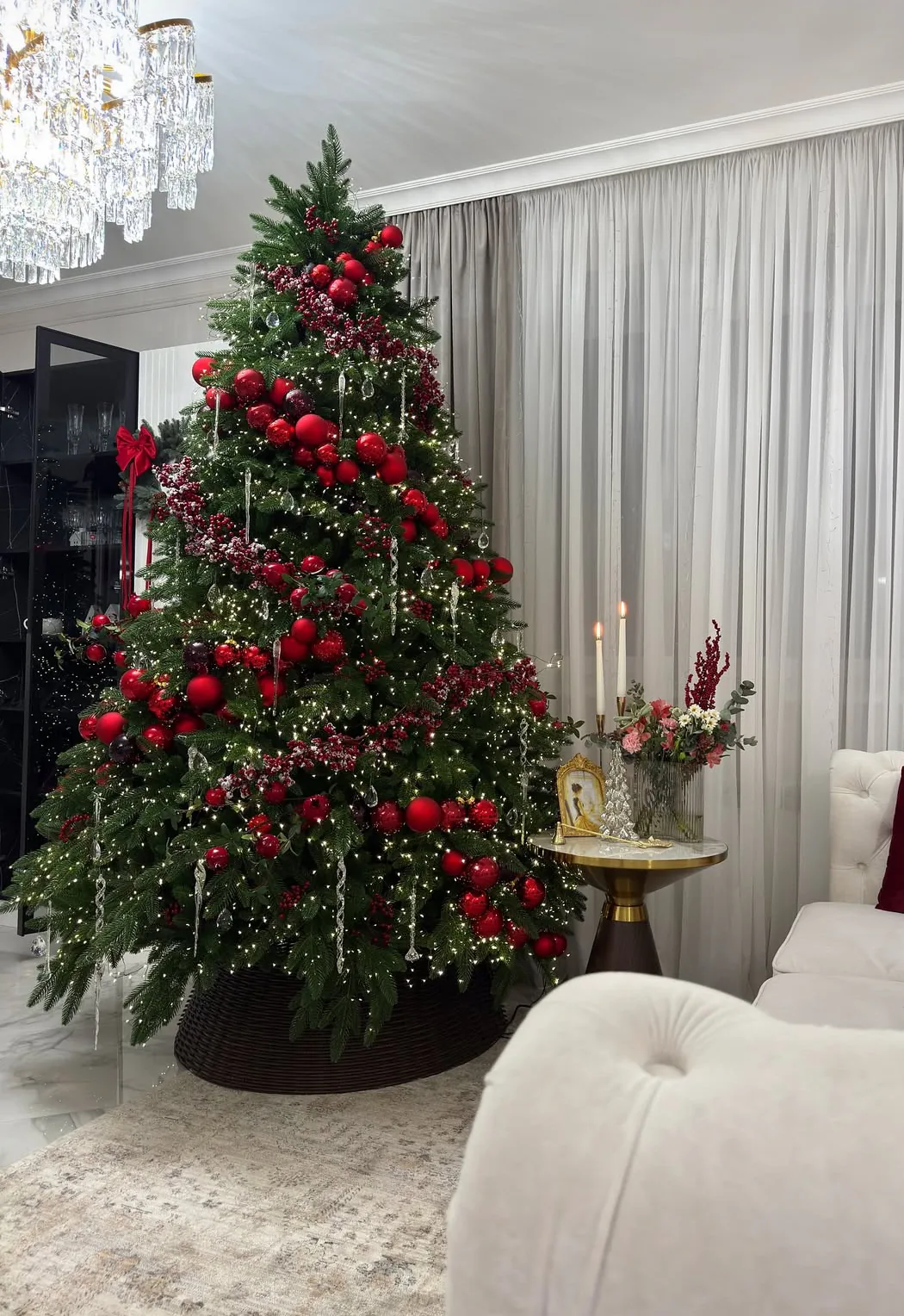 Brad de Crăciun în decor clasic roșu, cu lumini calde, într-un living elegant