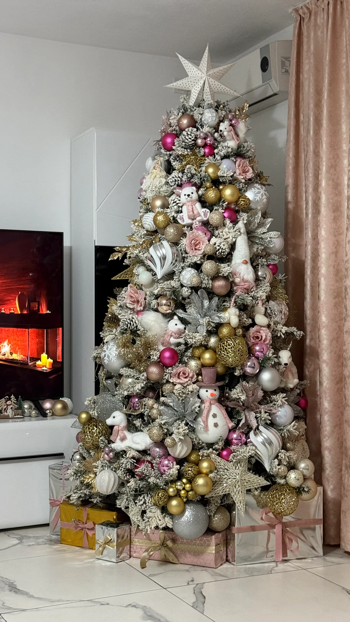 Brad de Crăciun decorat în auriu, alb și roz, într-un living cu șemineu