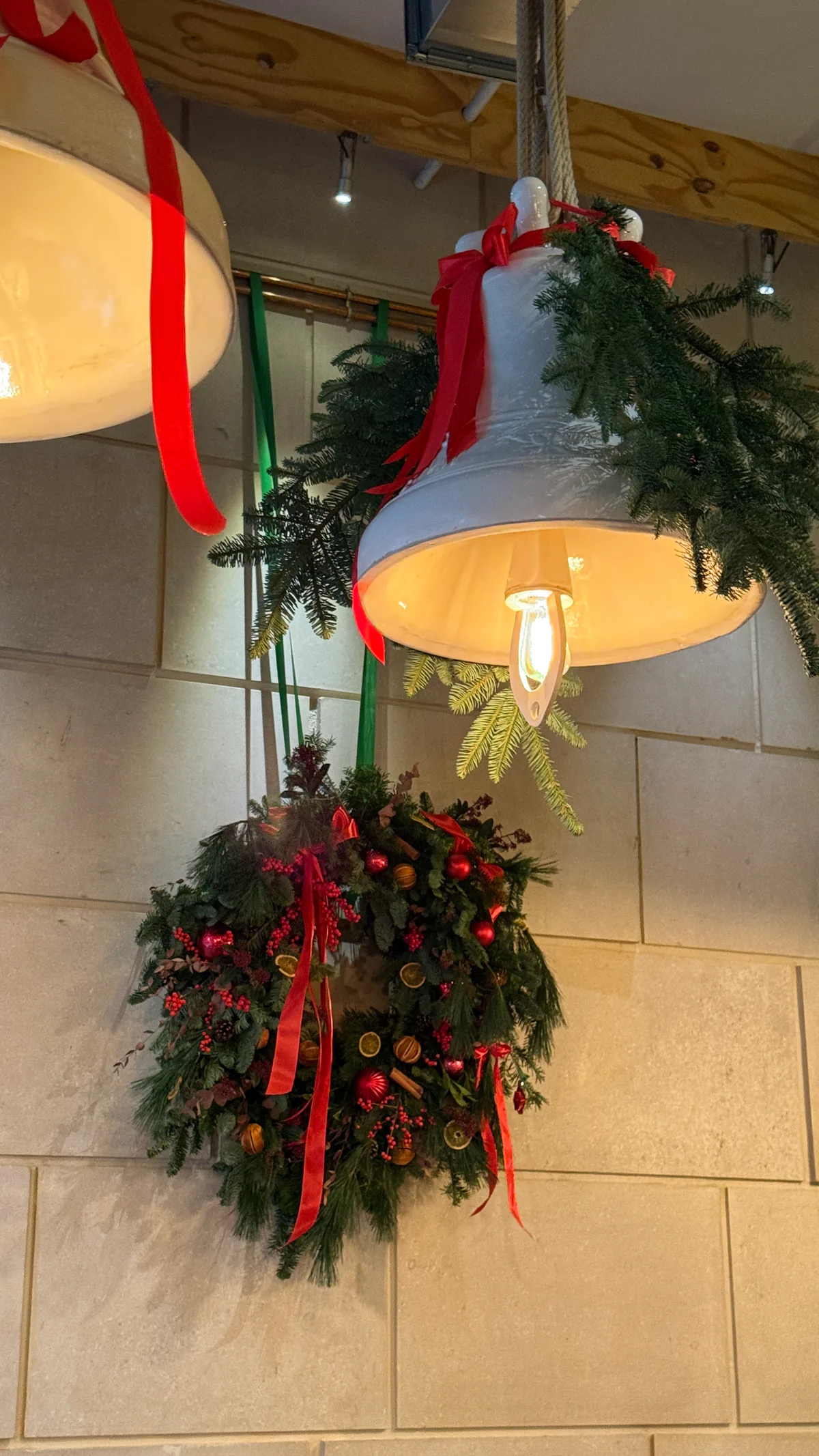 Coroniță de Crăciun cu globuri roșii și panglici, montată pe peretele unui restaurant