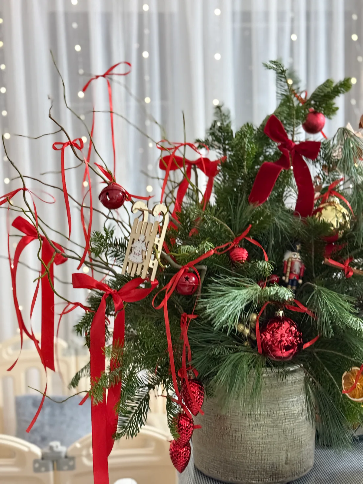 Decor de Crăciun cu brad în ghiveci, panglici roșii și ornamente din lemn