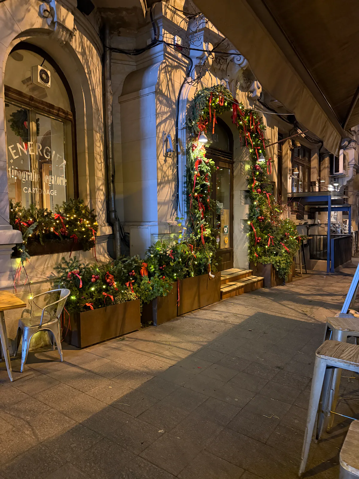 Fațada unui restaurant decorată de Crăciun, cu jardiniere cu cetină și lumini