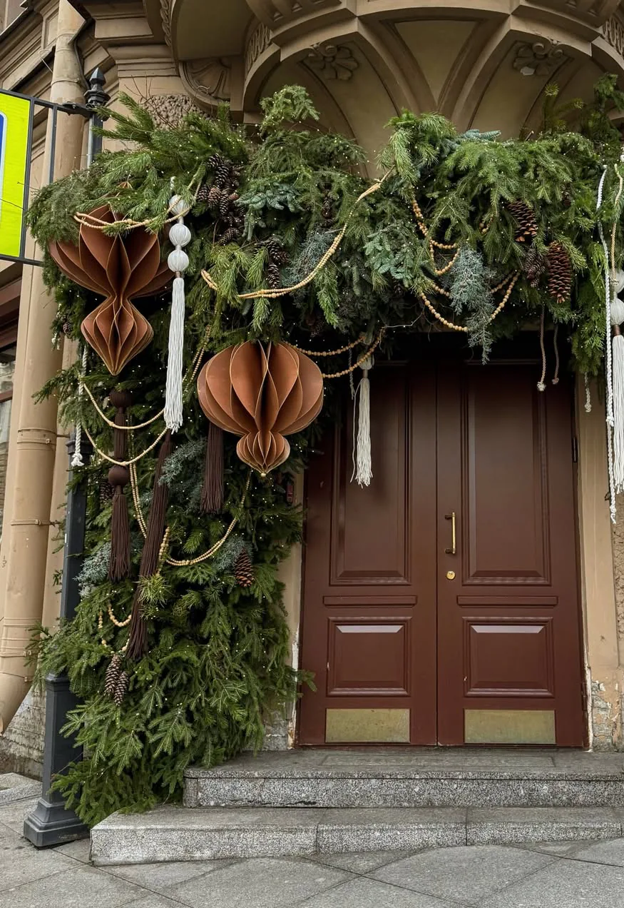 Intrarea unei clădiri decorată de Crăciun cu ghirlandă de brad și ornamente din hârtie