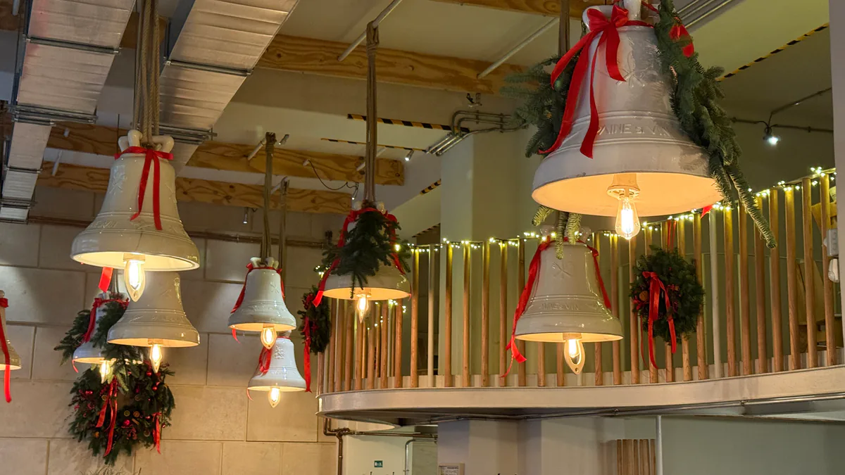 Decor de Crăciun într-un restaurant: ghirlande de cetină și funde roșii pe lămpile-clopot