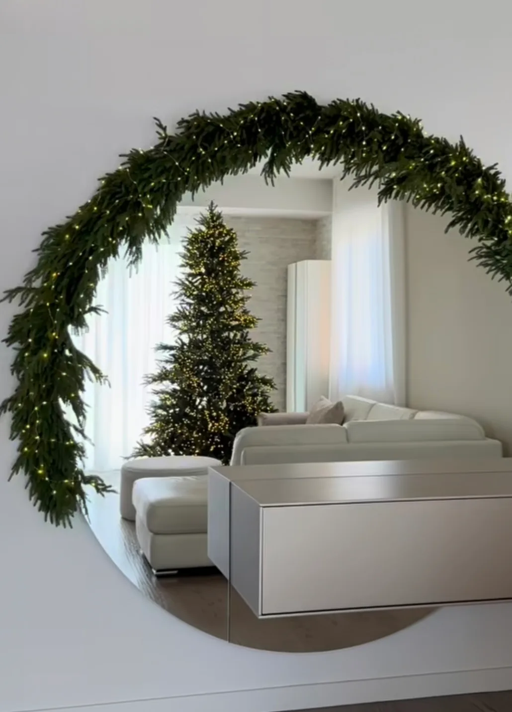Ghirlandă de brad cu lumini, montată pe o oglindă rotundă într-un interior minimalist