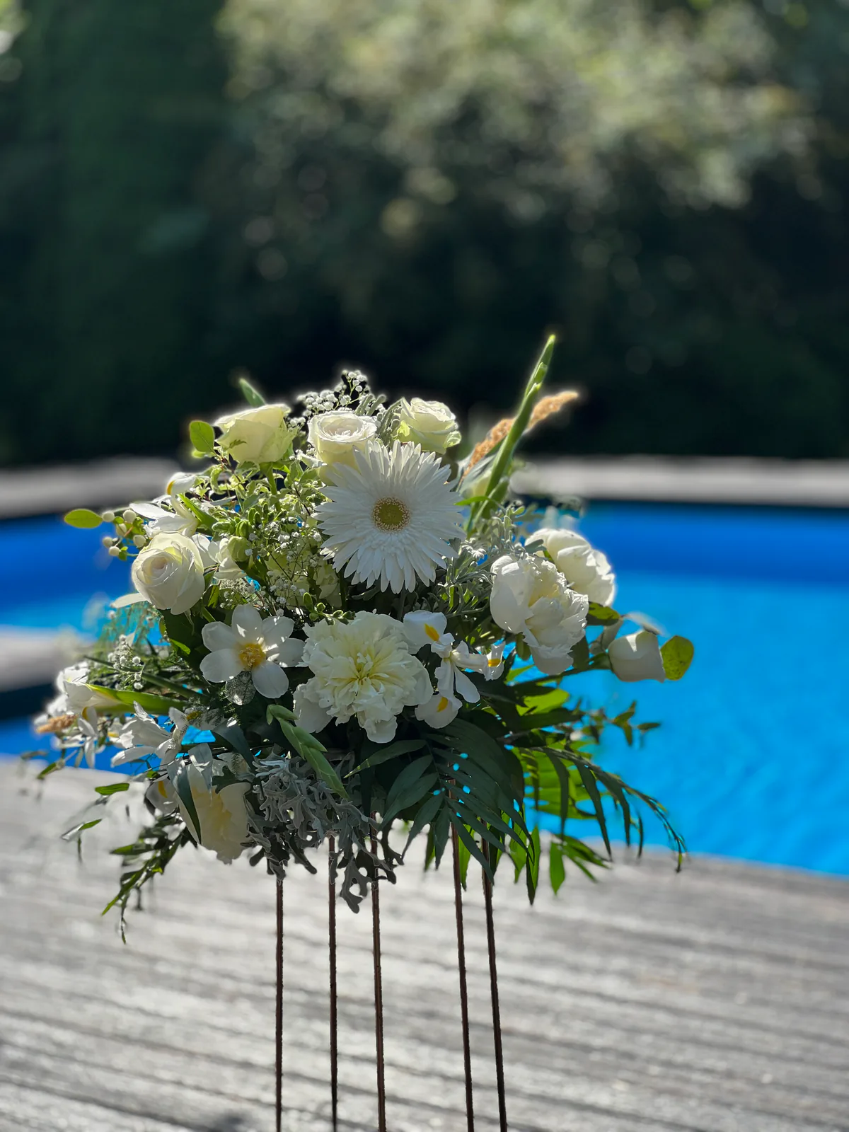 Aranjament floral alb pe suport înalt, la un eveniment în aer liber