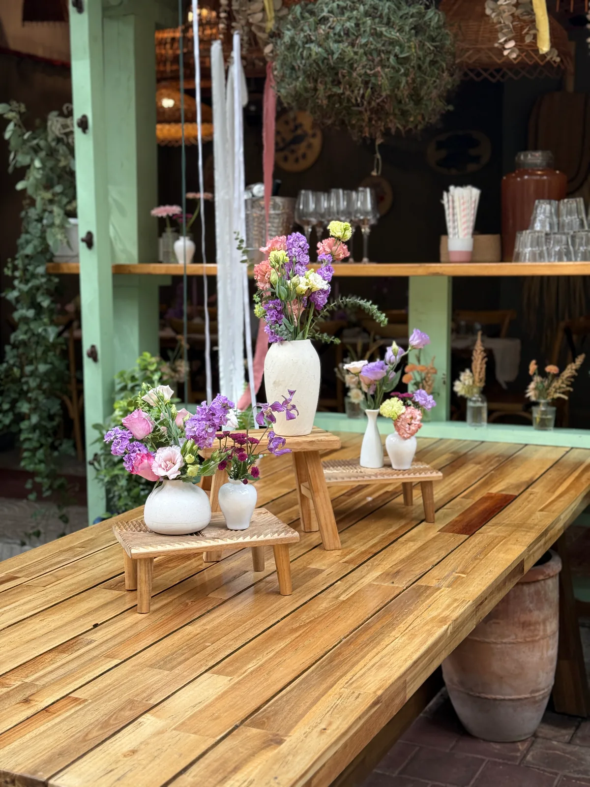 Aranjamente florale pastel pe suporturi din lemn, pe terasa unui local